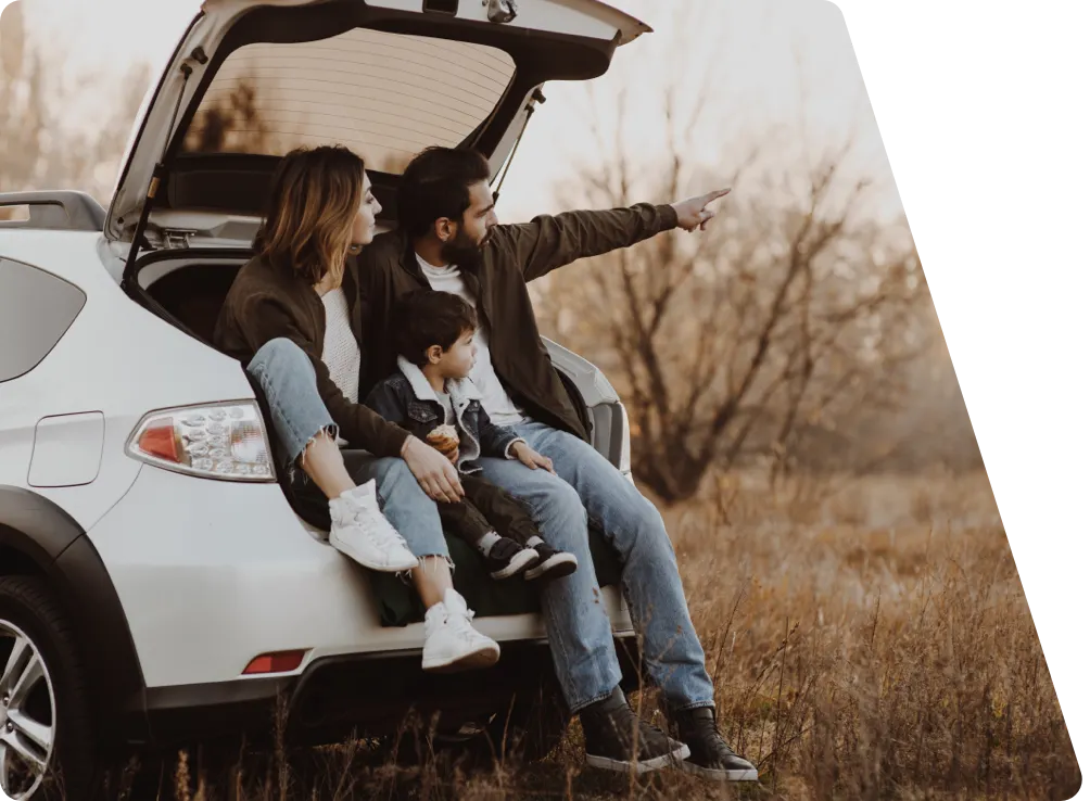 Una familia sentada en su coche nuevo, disfrutando de un momento juntos al aire libre.